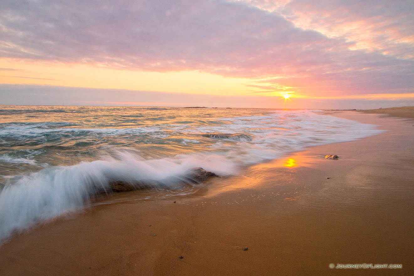 Waves of the Pacific crash on the shore of Crystal Cove State Park in California while the sun sets in the distance. - State of California Picture