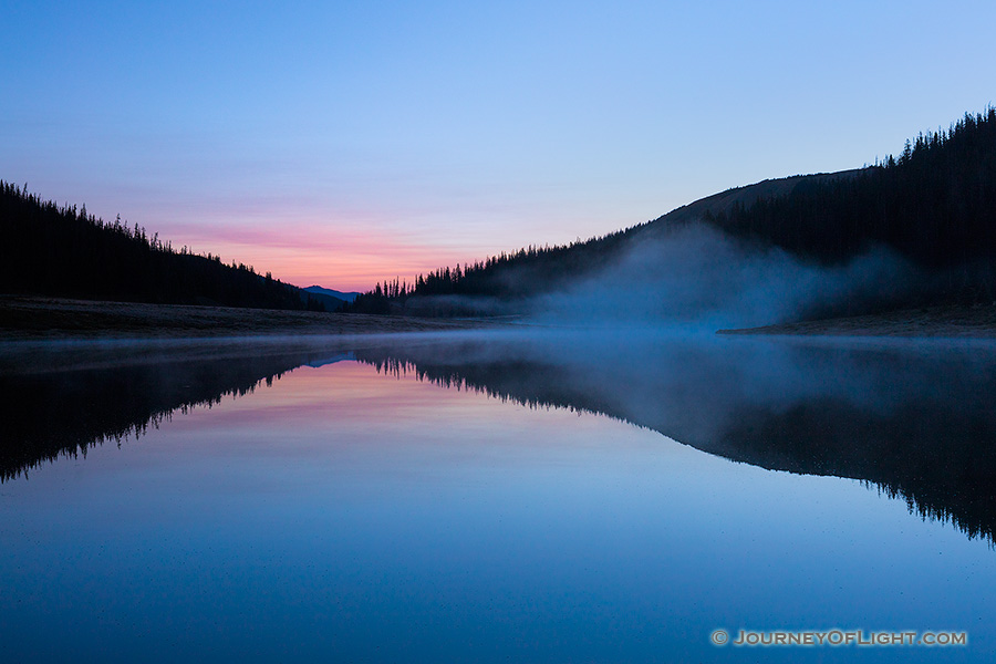 While a hint of red glows in the distance, cool blue hues dominate the sky just before sunrise over Poudre Lake in Rocky Mountain National Park. - Colorado Photography