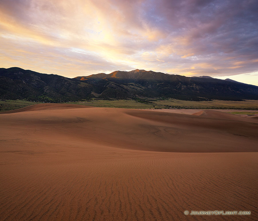 Sunlight streams through a pass in the Sangre de Cristo Mountains and illuminates the peak of Carbonate Mountain just southeast of the dunes at Great Sand Dune National Park. - Colorado Photography