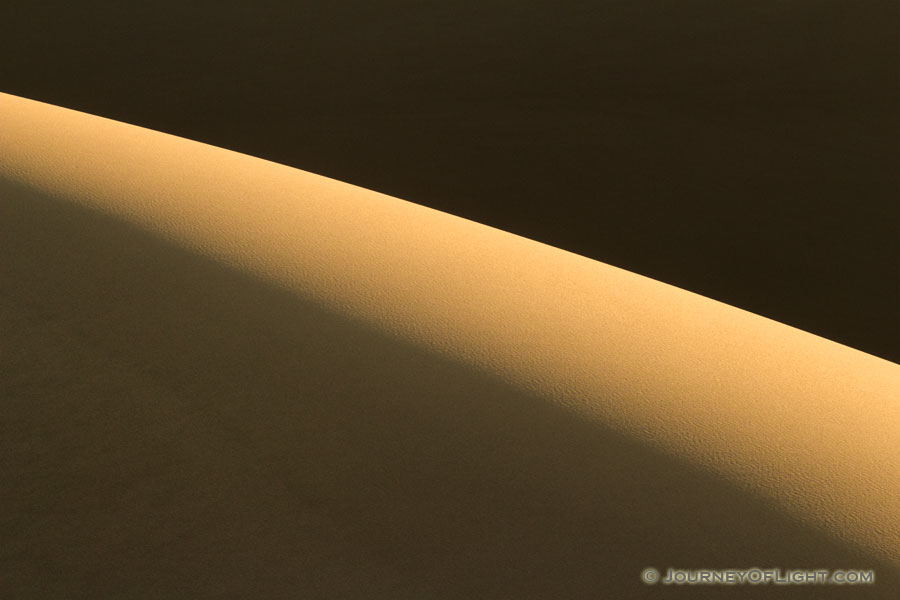 Morning sun streams across Great Sand Dune National Park and Preserve illuminating the tops of the dunes. - Colorado Photography