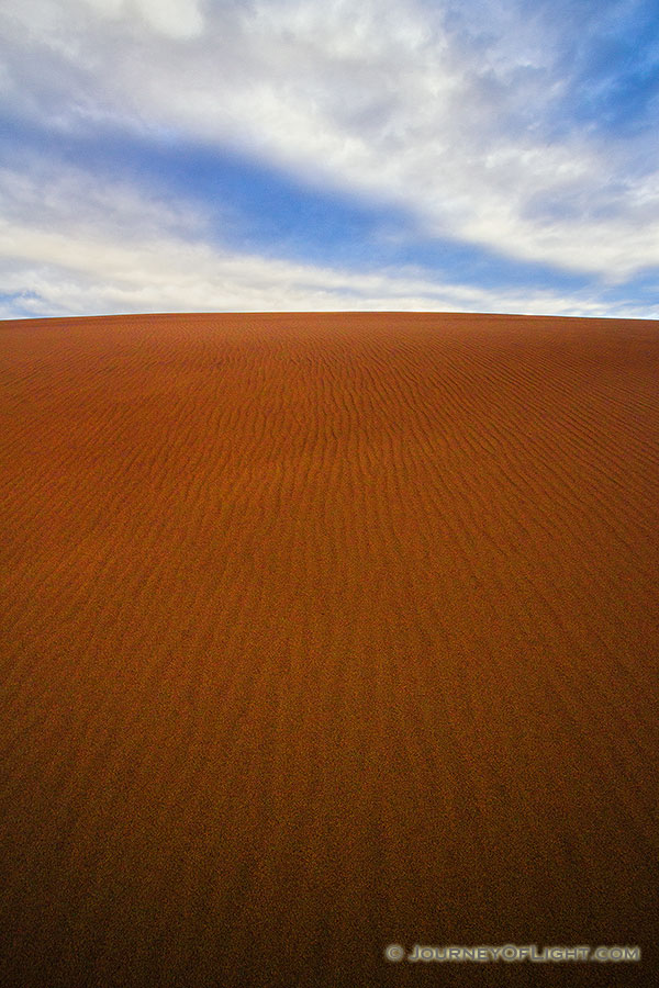 From the base of a tall dune looking skyward, clouds float above the dunes at Great Sand Dune National Park. - Colorado Photography