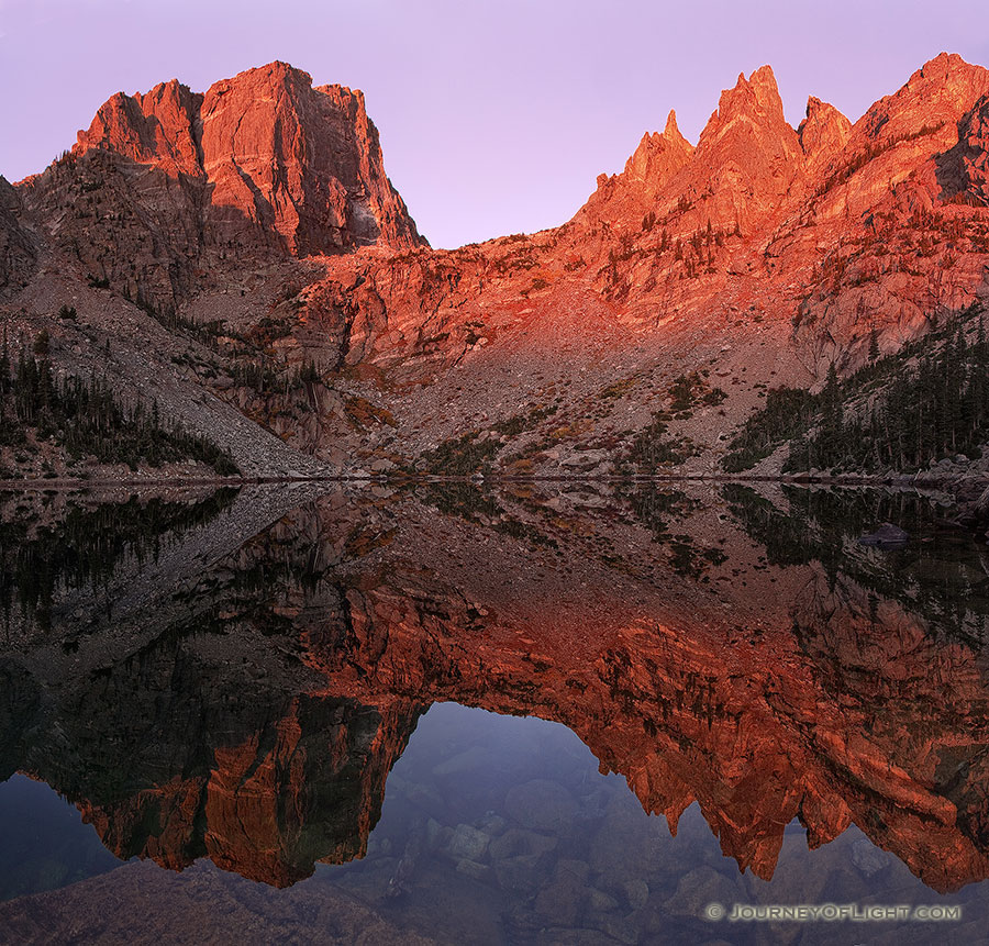 Unusually calm, Emerald Lake reflects a perfect and symmetrical image of the grand Hallet Peak and Flattop Mountain illuminated with alpenglow.  The only sounds on this quiet morning are the flow of a waterfall across the lake and the chirping of a nearby Steller's Jay. - Rocky Mountain NP Photography