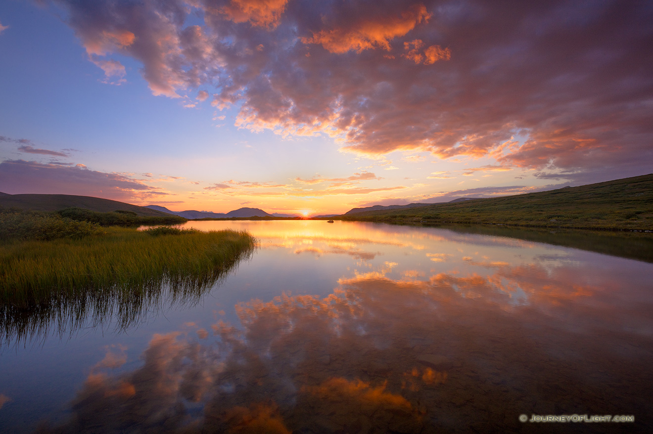 Glowing with intensity, clouds drift above a tarn near Independence Pass in the White River National Forest in Colorado. - Colorado Picture