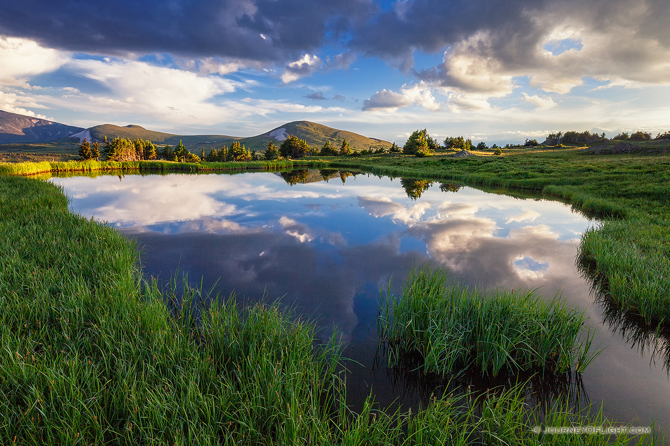 An idyllic mountain scene on the tundra of Rocky Mountain National Park.  A small tarn reflects the beautiful sky and the mountains in the distance. - Colorado Picture