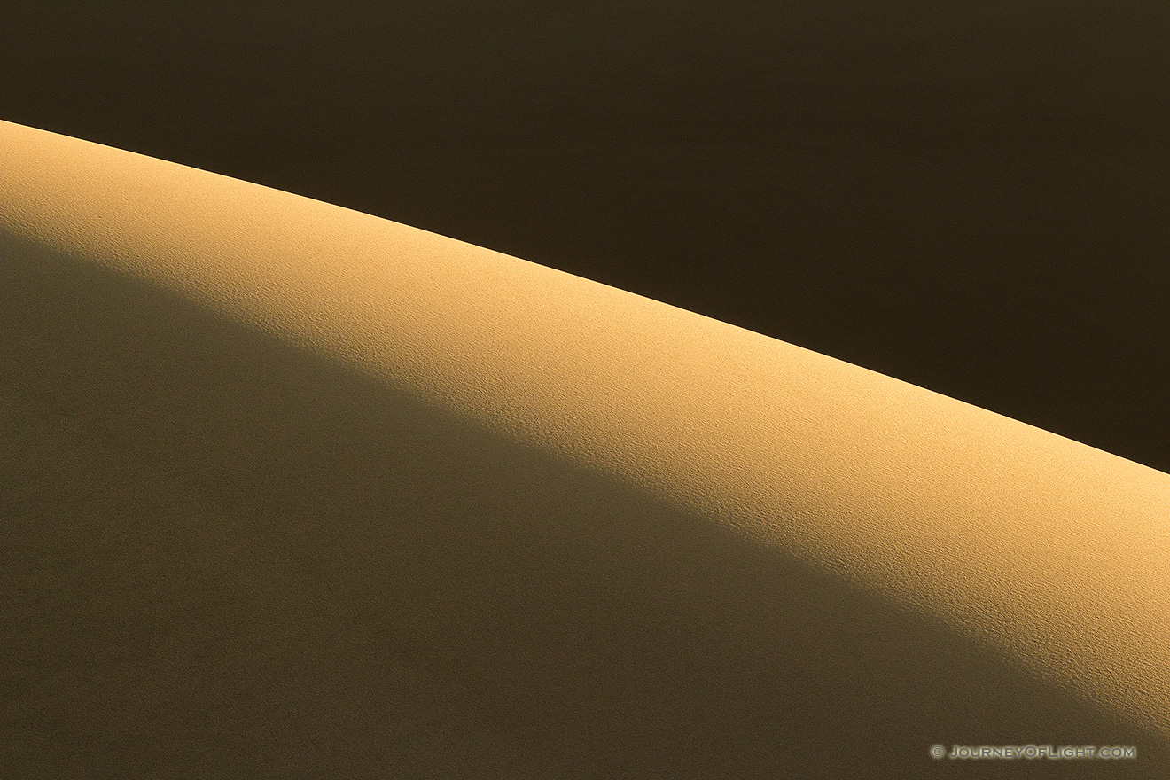 Morning sun streams across Great Sand Dune National Park and Preserve illuminating the tops of the dunes. - Colorado Picture