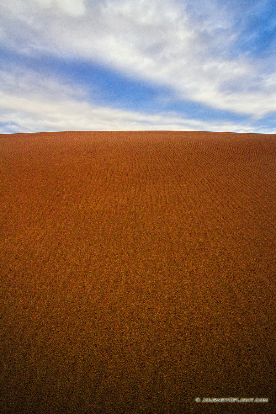 From the base of a tall dune looking skyward, clouds float above the dunes at Great Sand Dune National Park. - Colorado Picture