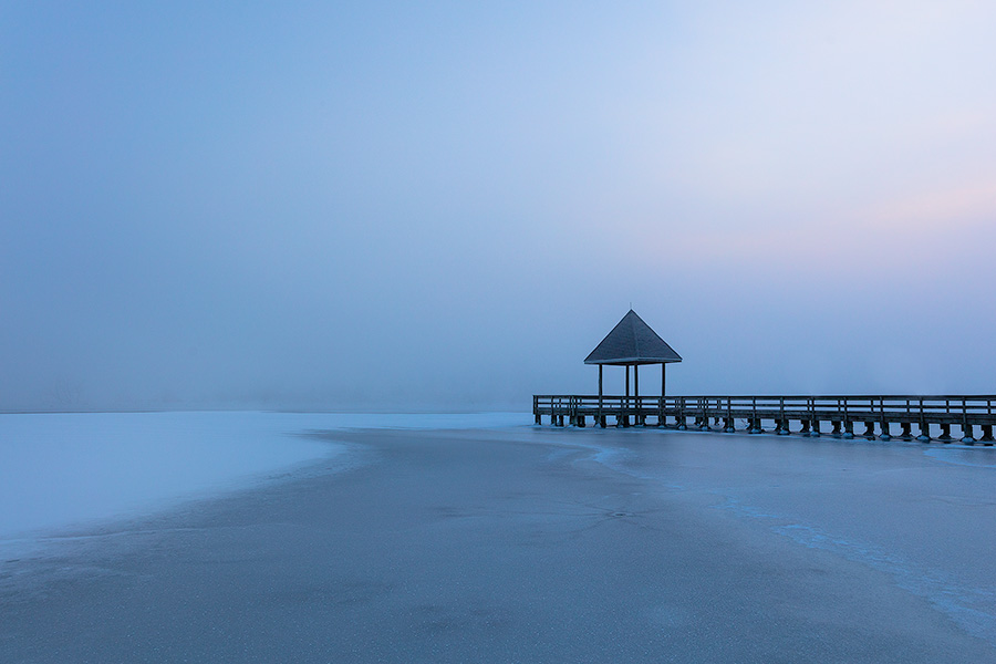 A scenic landscape photograph of fog over a frozen lake and a dock at Walnut Creek, Nebraska. - Nebraska Photography