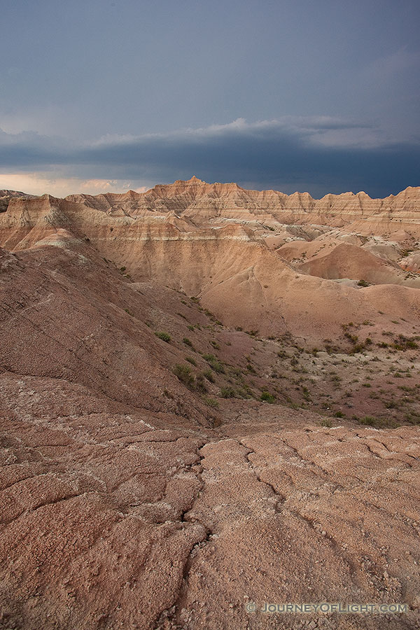 As a storm passes over Badlands National Park in South Dakota, dark clouds contrast with the desolate landscape. - South Dakota Photography