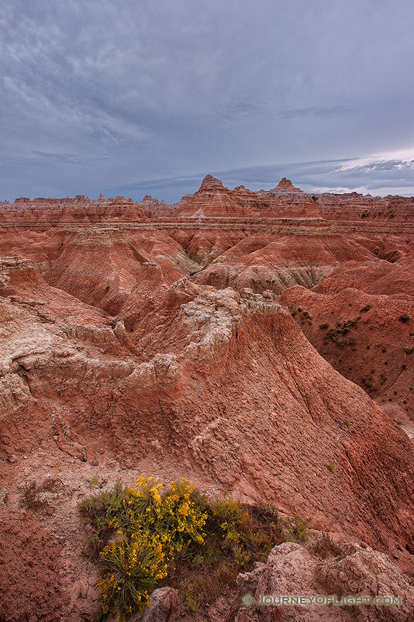 Afternoon storm clouds gather over the rock formations deep in Badlands National Park as a waning moon gentle descends behind. - South Dakota Photography