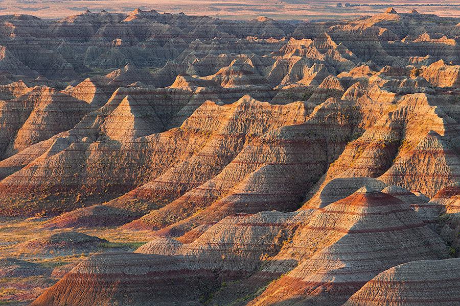 The warm light of the recently risen sun illuminates the Badlands of South Dakota in Badlands National Park. - South Dakota Photography