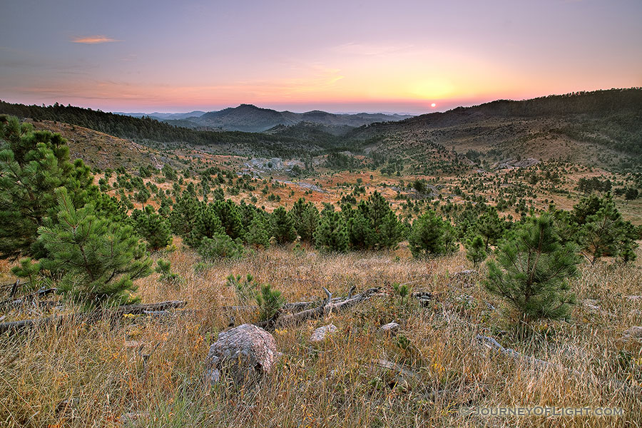 In the distance the sun rises above the peaks of the Black Hills in Custer State Park in South Dakota. - South Dakota Photography