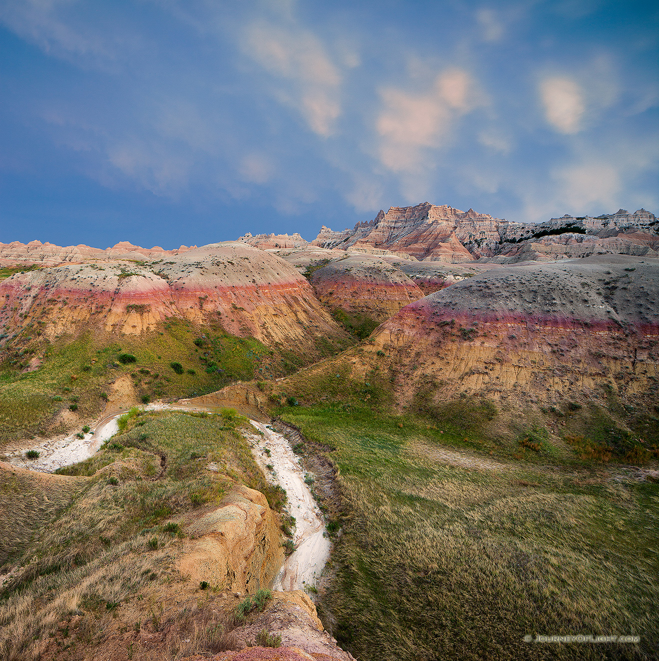 On a warm summer evening as I was photographing Badlands National Park in South Dakota, I could hear thunder in the distance.  As I continued to capture the landscape a patch of mammantus clouds began to creep closer.  Generally associated with severe thunderstorms, I began to get my gear ready in case things turned bad and I had to leave quickly.  Luckily, the wind shifted and the storm began to move away, just at the last light of day began to peak through the remaining clouds in the west illuminating the landscape. - South Dakota,Landscape Picture