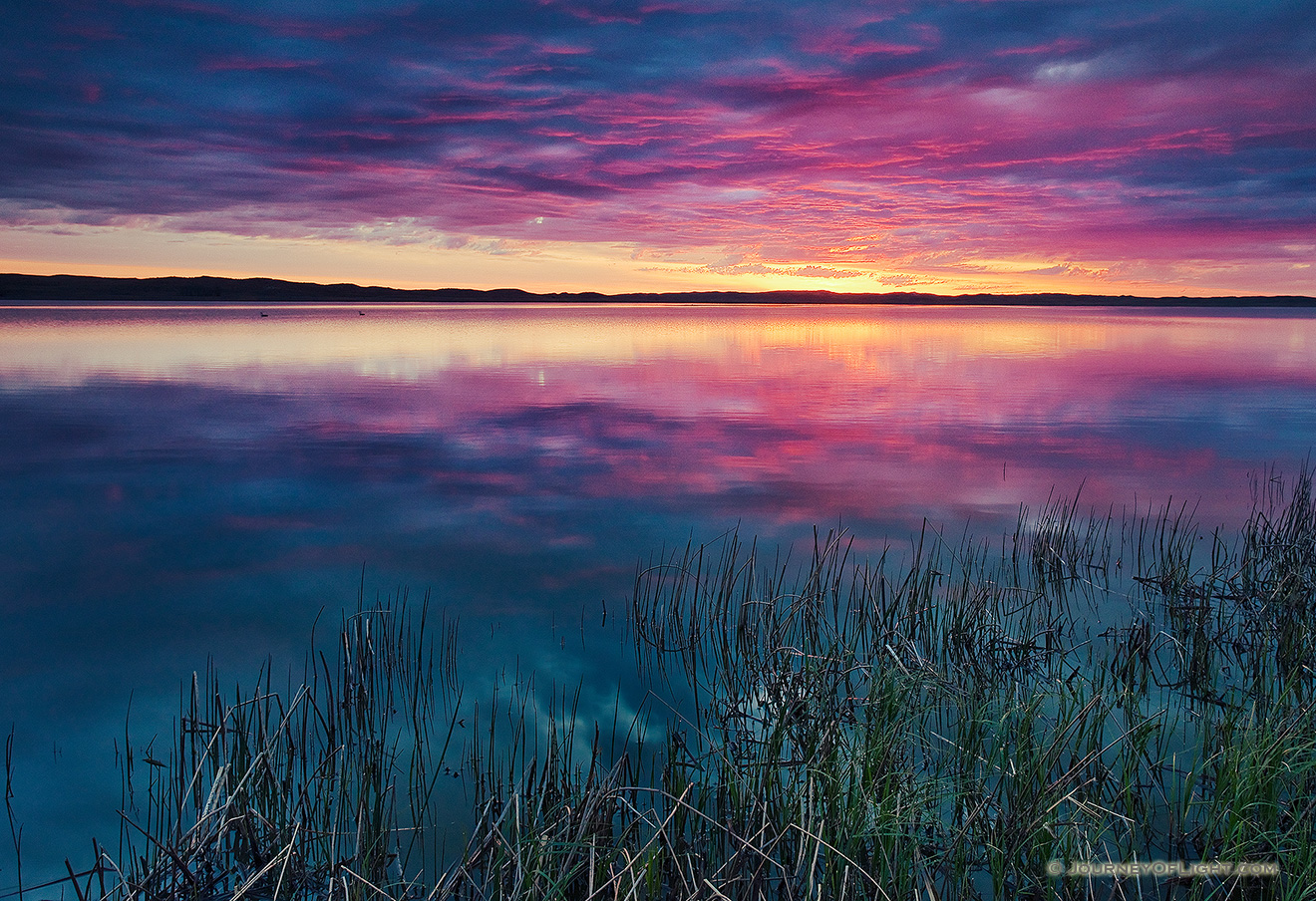 A small lake nestled in the Sandhills reflects the rising sun on a cool spring morning. - Valentine Picture