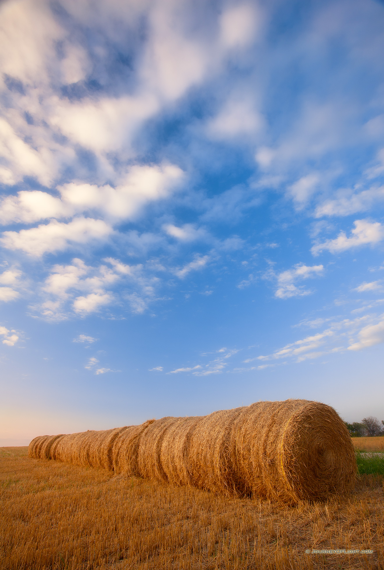 Puffy clouds form in the late evening above a row of hay bales in eastern Nebraska. - Nebraska Picture