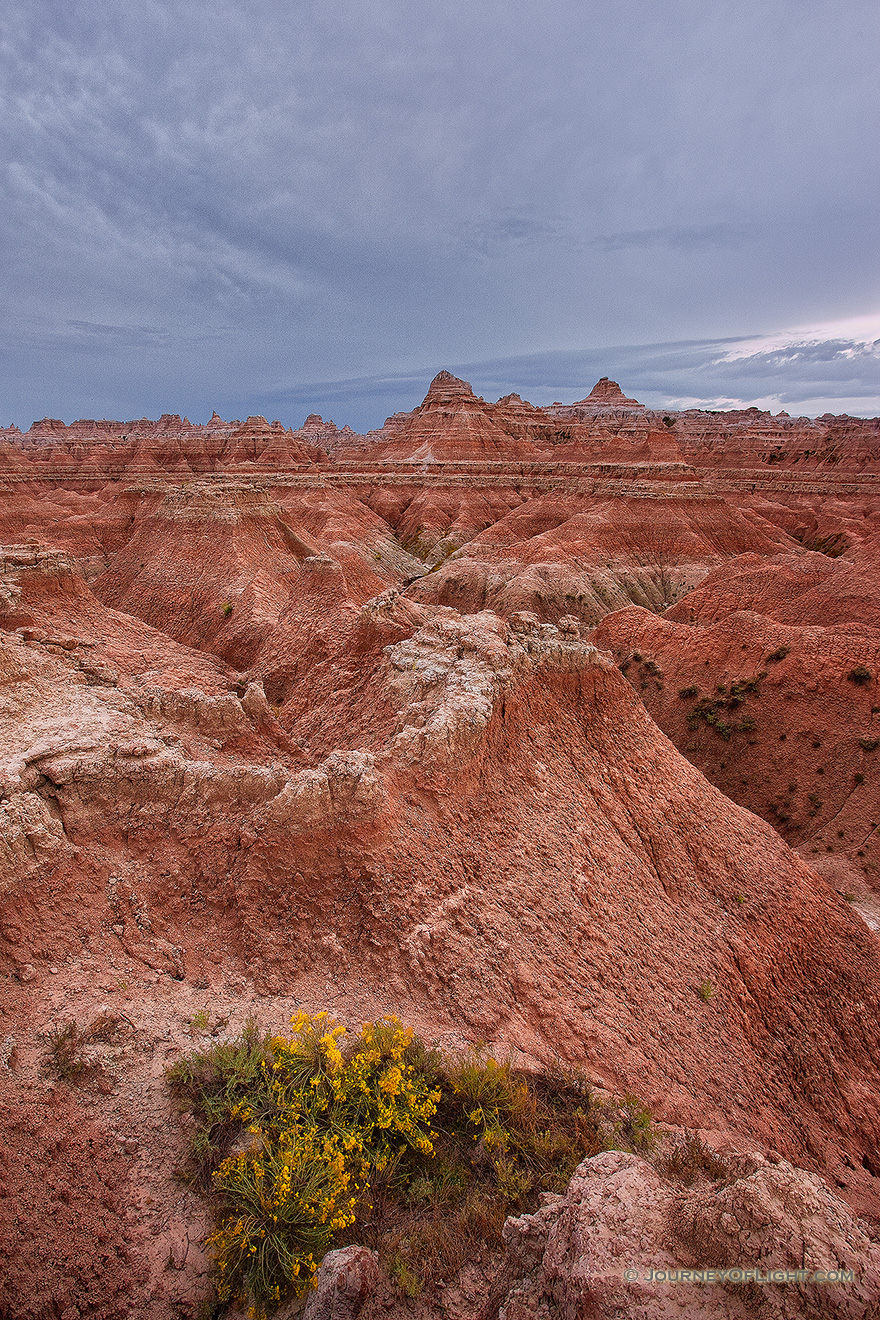 Afternoon storm clouds gather over the rock formations deep in Badlands National Park as a waning moon gentle descends behind. - South Dakota Picture