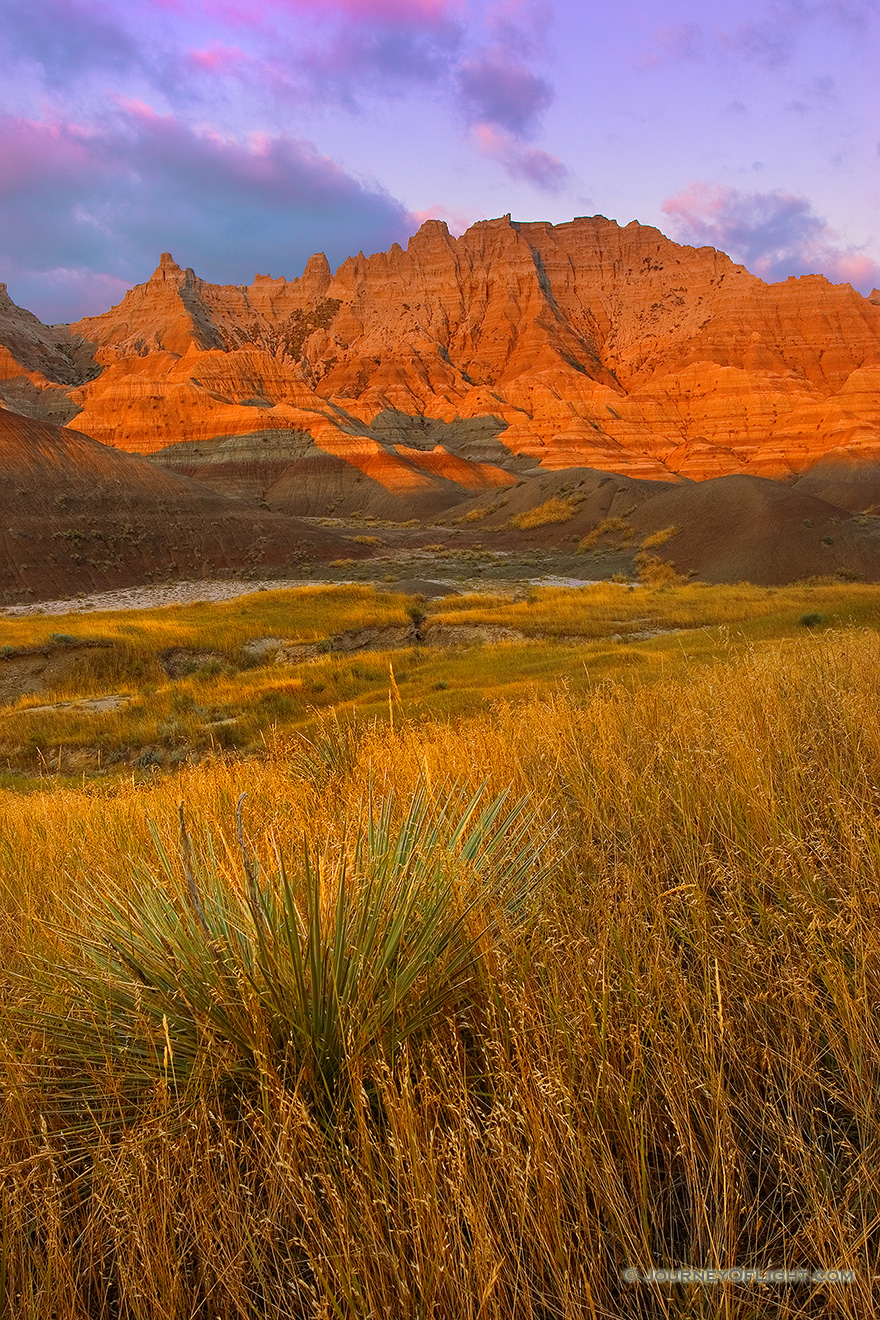 The morning sun emits a glow that radiates orange off the unusual formations in the Badlands National Park. - Badlands NP Picture