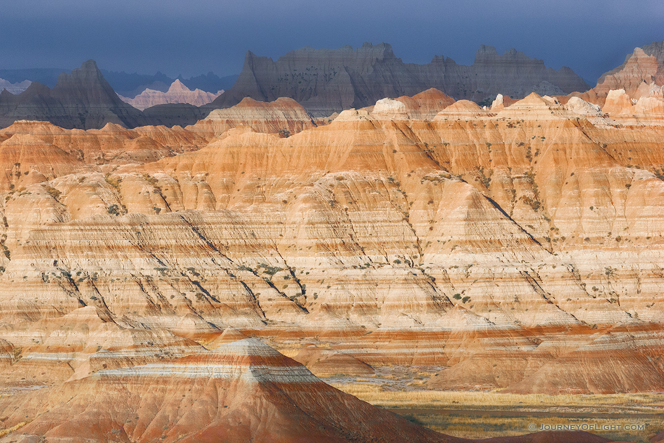 As a storm clears over the badlands light from the sun illuminates the rock formations while the dark clouds still dominate the sky in the distance. - South Dakota Picture