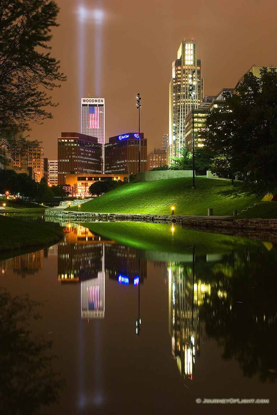 On September 11, 2006 Omaha, Nebraska paid tribute to the victims of 9/11 by hanging 2 large United States flags on the Woodmen tower and by shining two large lights into the sky. - Omaha Picture