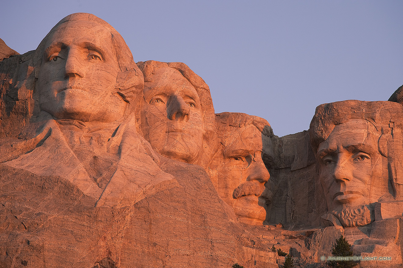 The warm sunrise light illuminates the faces with a reddish hue. - Mt. Rushmore NM Picture