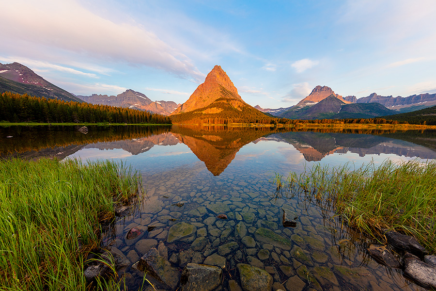 A scenic landscape photograph of sunrise on Swiftcurrent Lake, Glacier National Park, Montana. - Glacier Photography