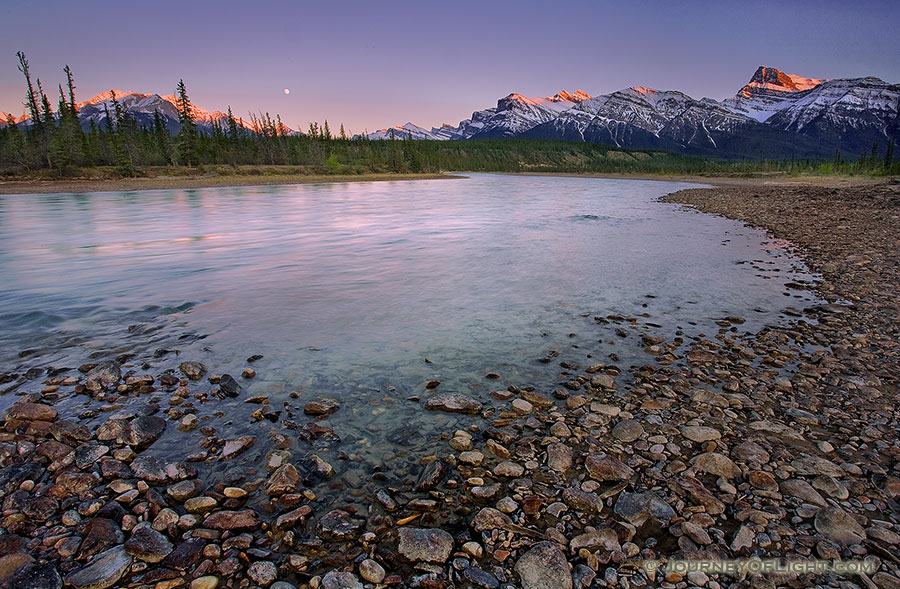 A nearly full moon rises above the Canadian Rockies while the last glow of the sun reflects off of the moutain tops. - Canada Photography